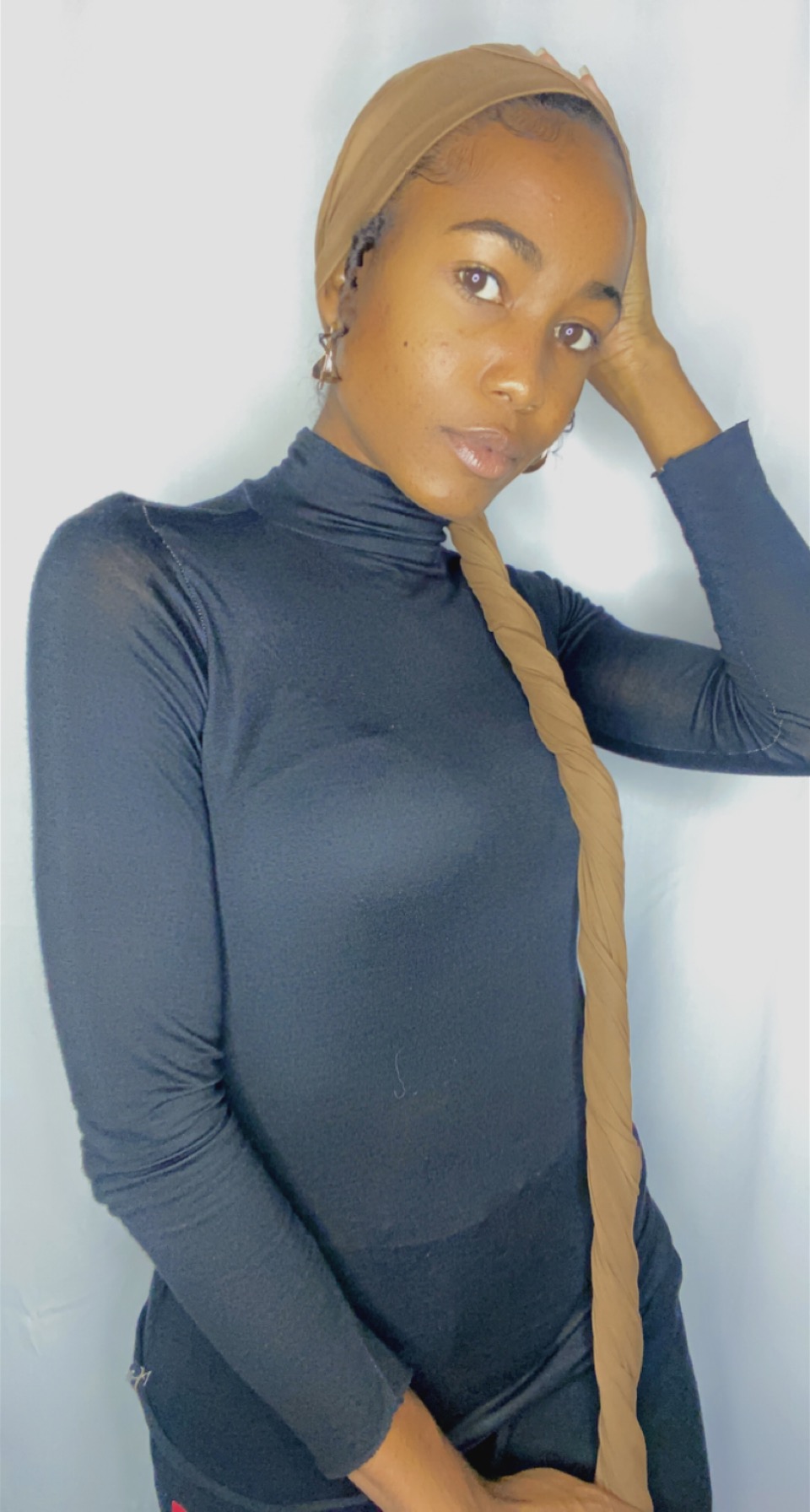 Woman in a camel Krown with the long tail draped forward over a navy turtleneck