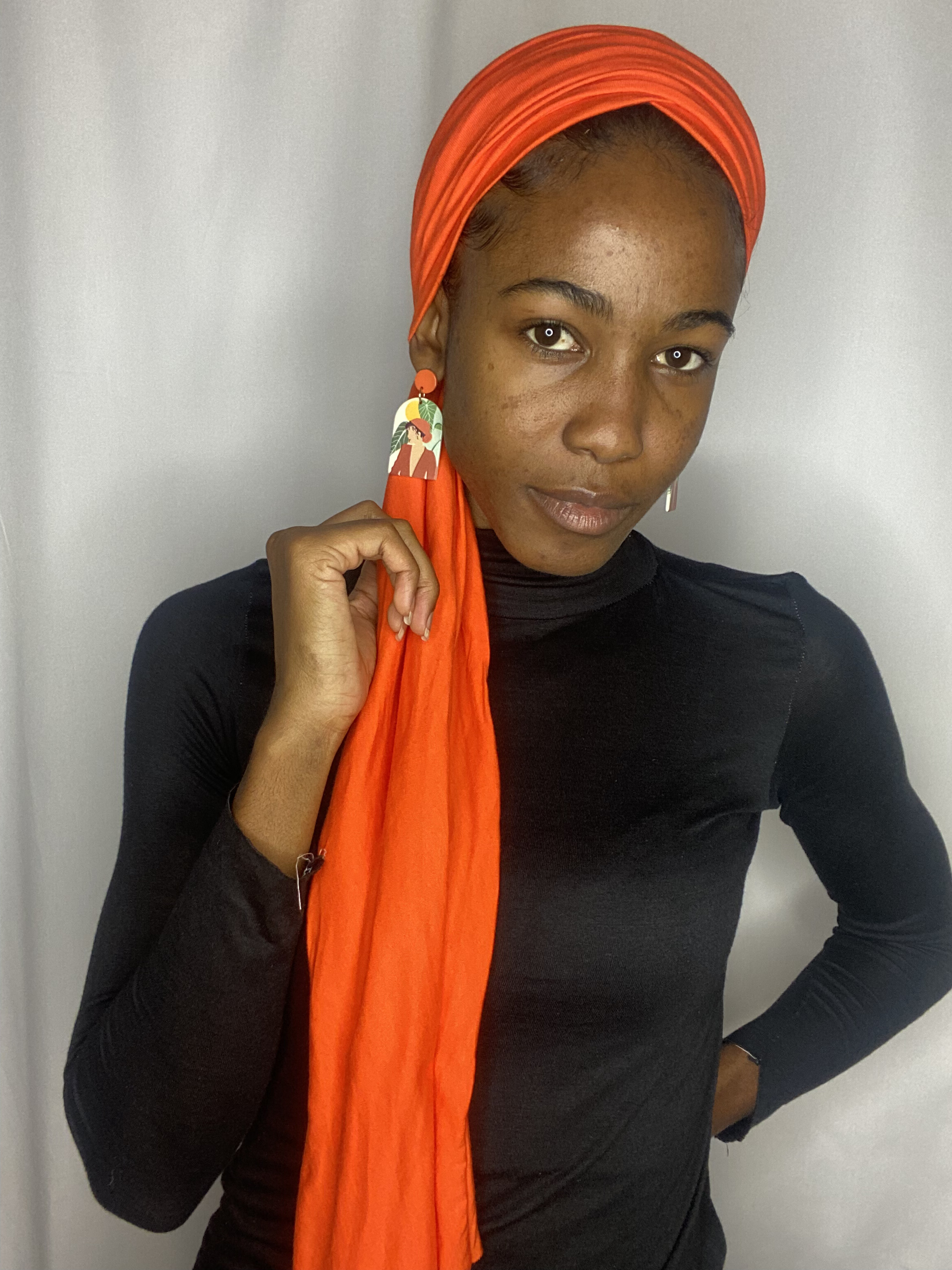 Portrait of a woman holding the long tail of a coral Krown over her shoulder