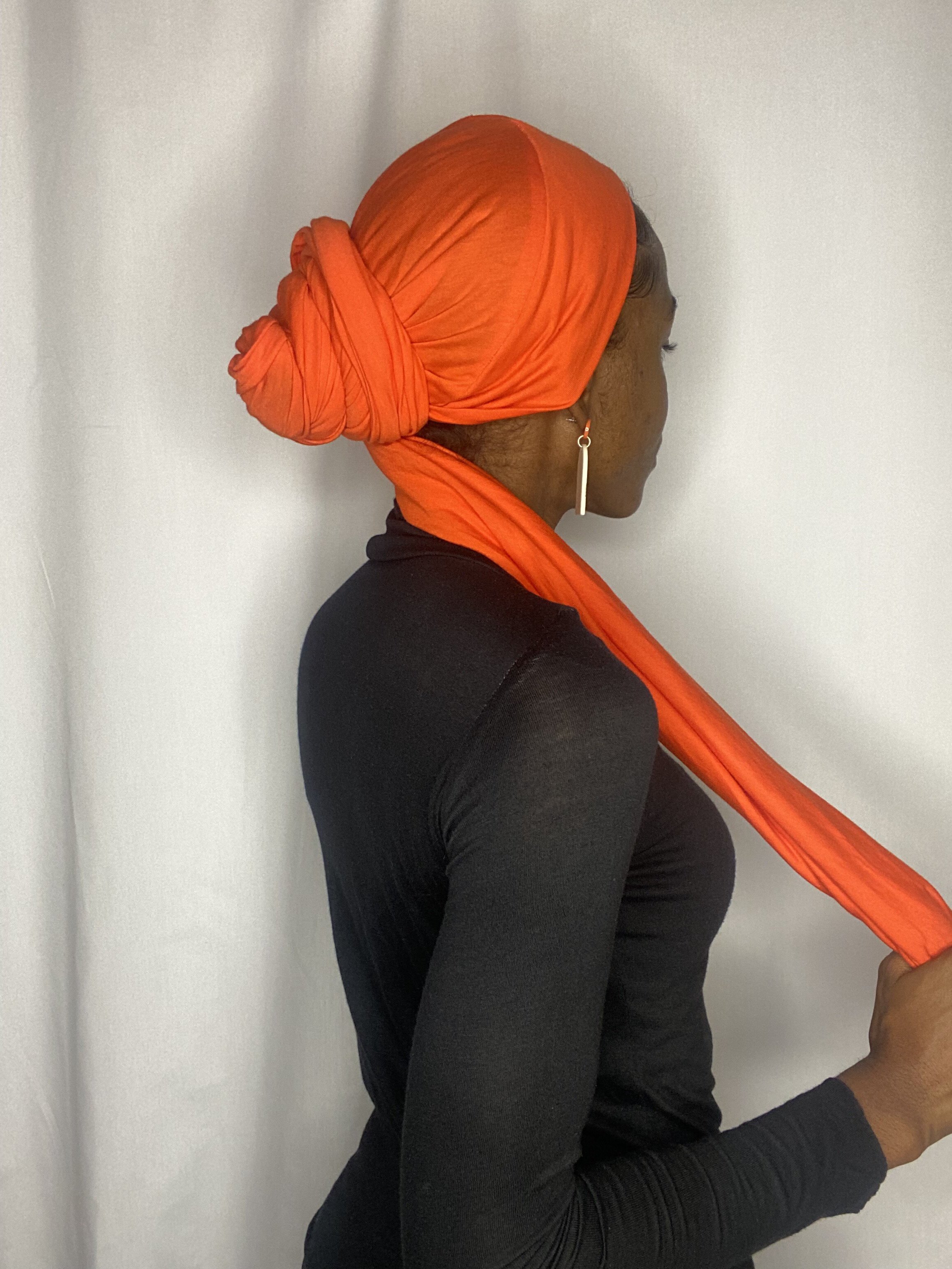 Back-and-side view of a woman wearing a full coral Krown wrap with the tail trailing down