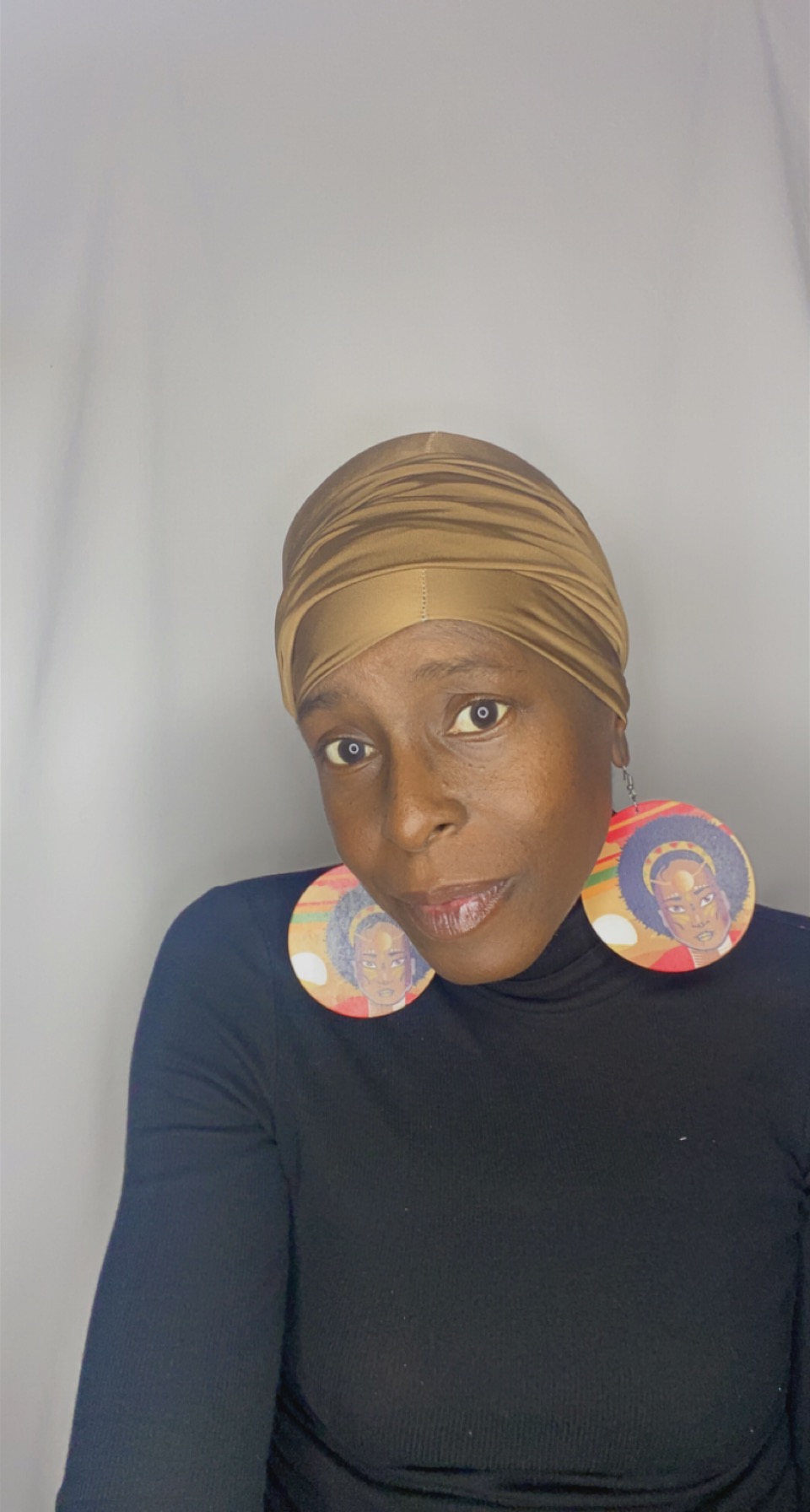 Portrait of a woman in a smooth camel Krown turban with bold afro-art statement earrings