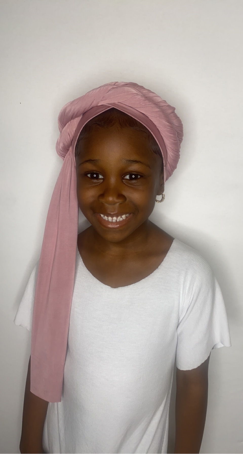 Young girl smiling while wearing a blush pink turban