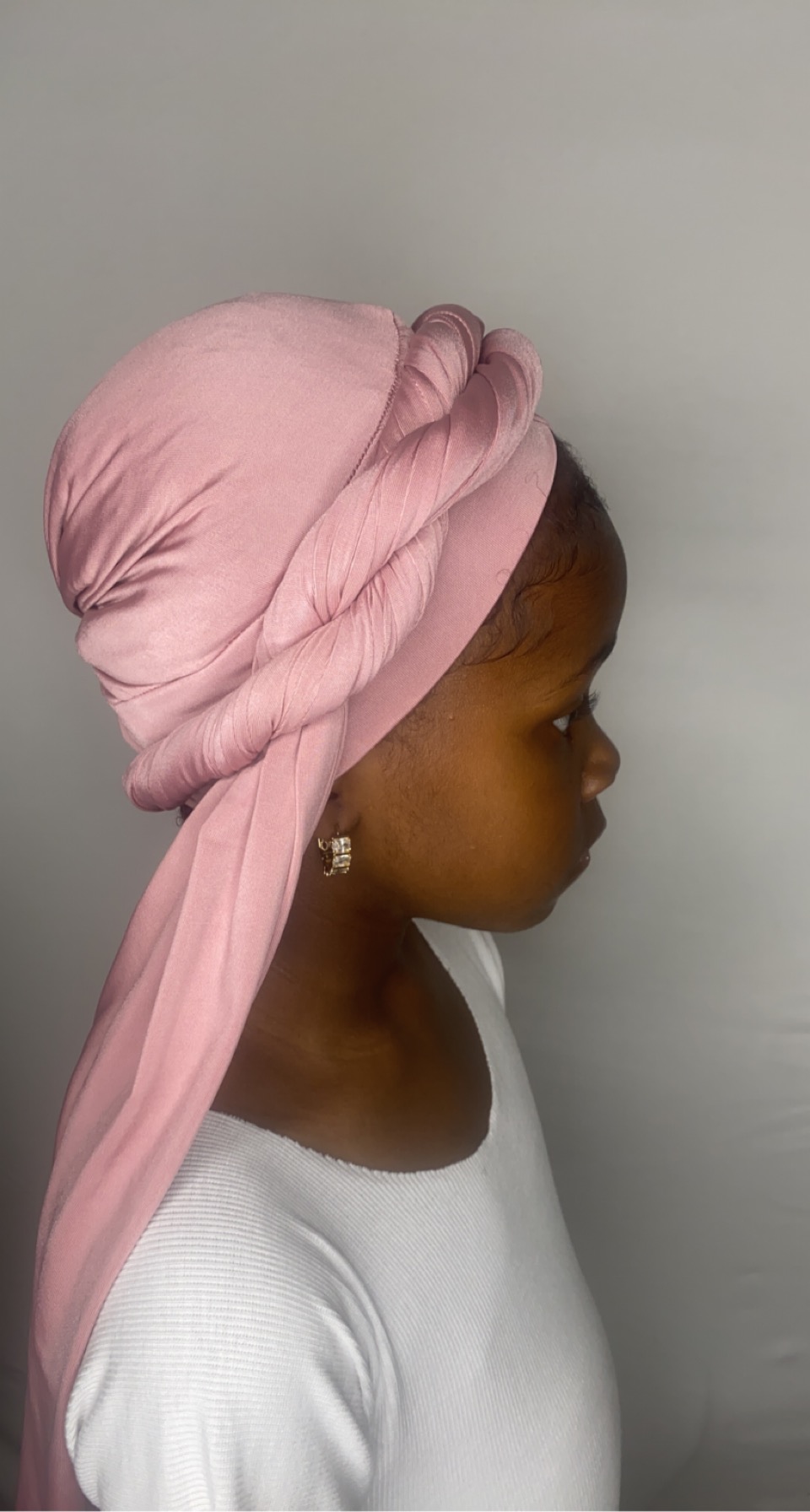 Young girl in a blush pink turban shown in side profile