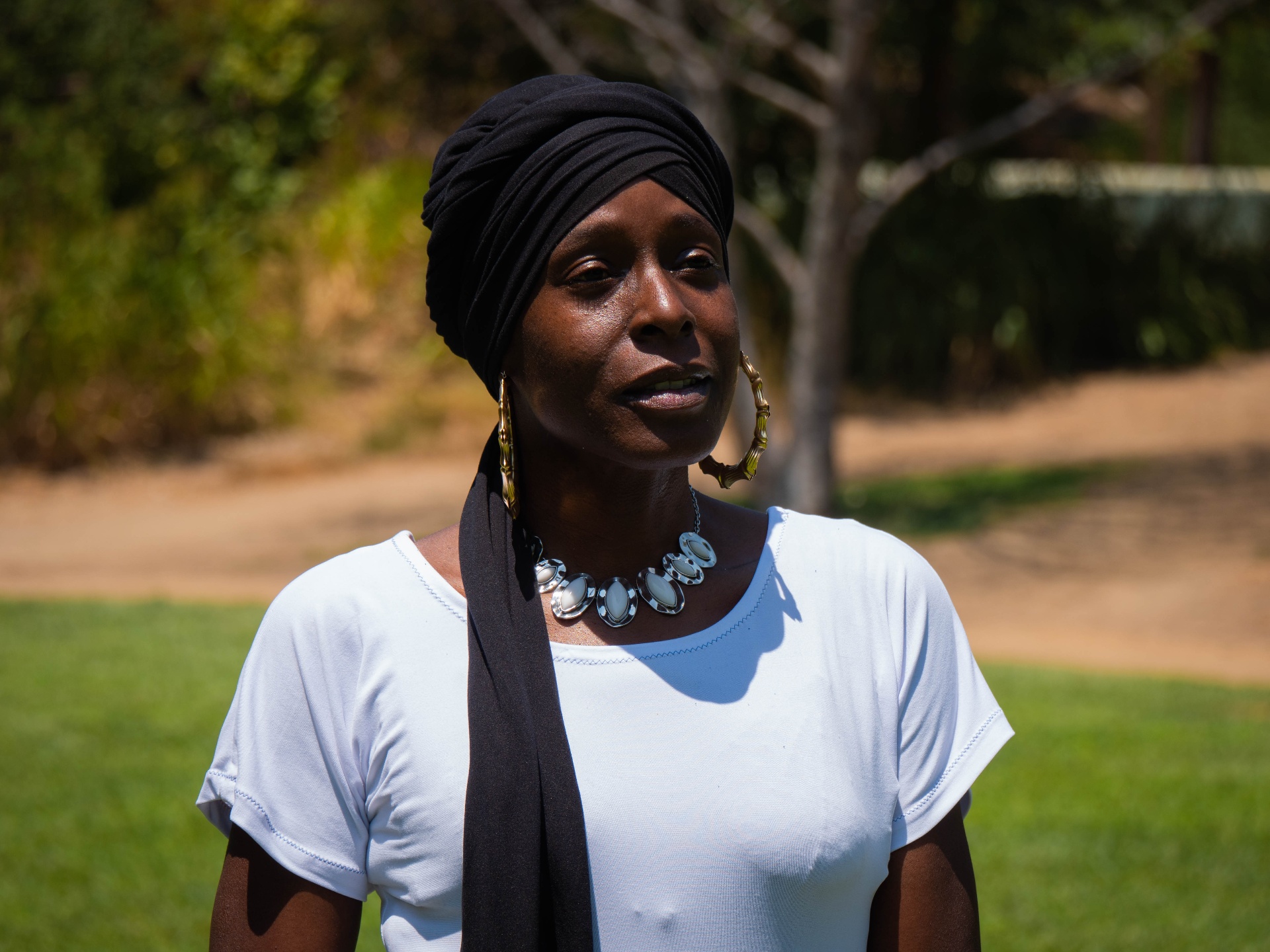Woman outdoors wearing a sleek black headwrap with silver jewelry