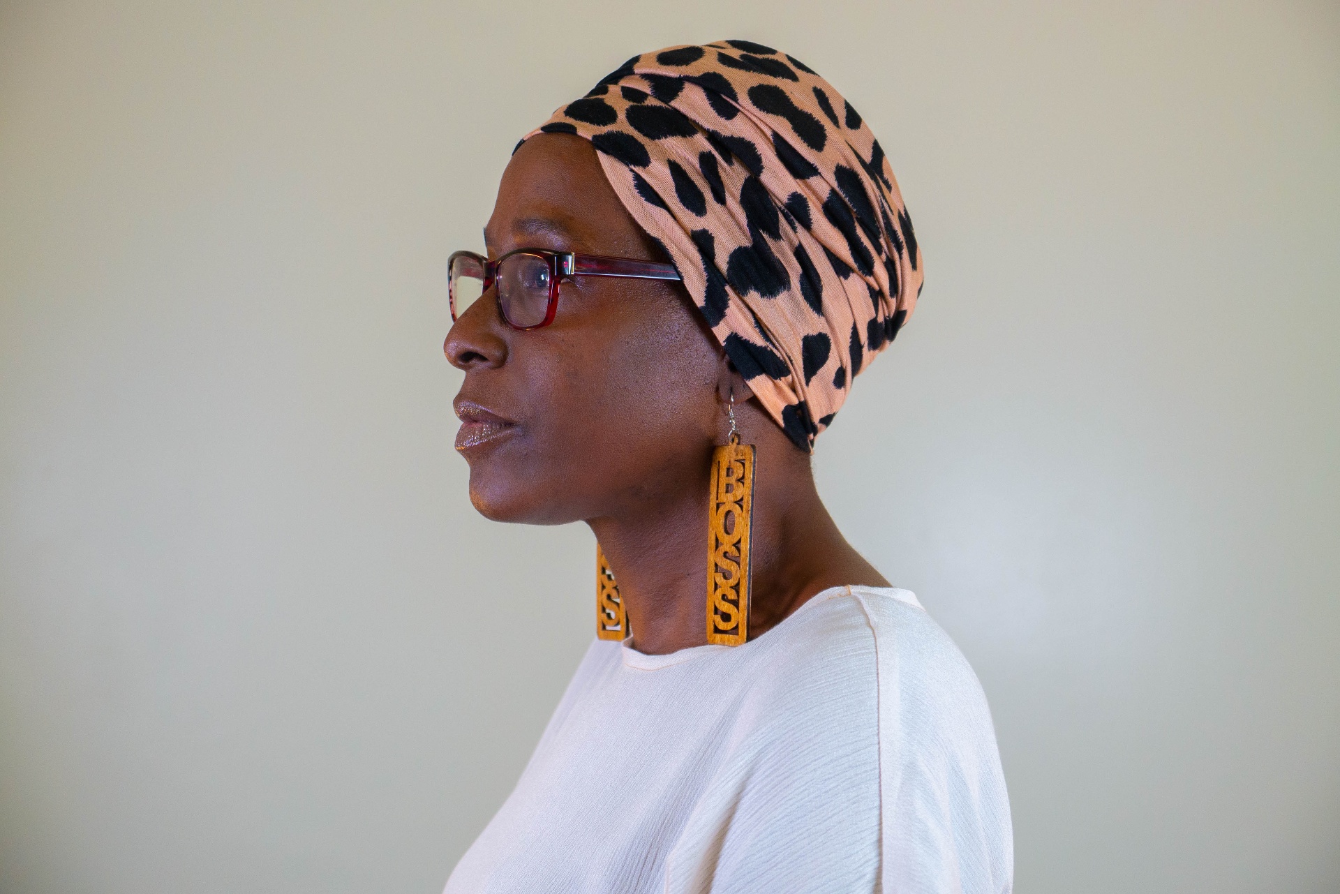 Profile portrait of a woman wearing a leopard print turban and statement earrings