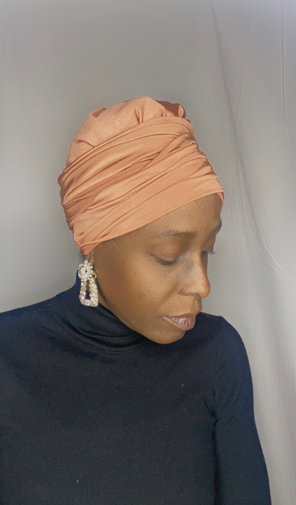 Woman wearing a soft peach Krown styled as a full crisscross wrap with crystal drop earrings