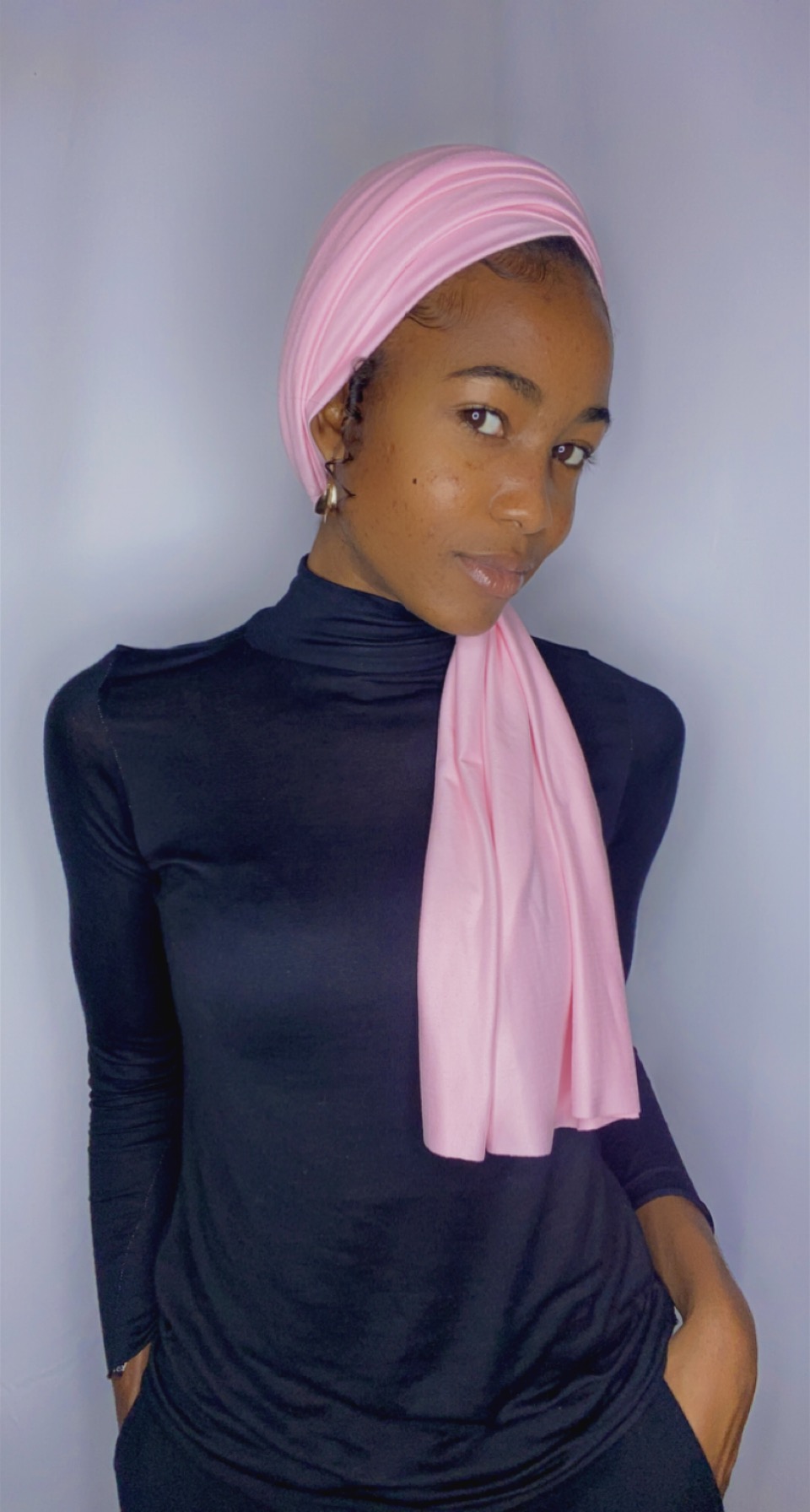 Side-glance portrait of a woman in a blush pink Krown with the long tail draped over one shoulder