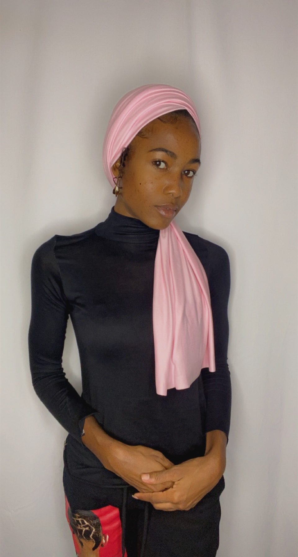 Woman wearing a blush pink Krown styled as a soft turban with a side-draped tail