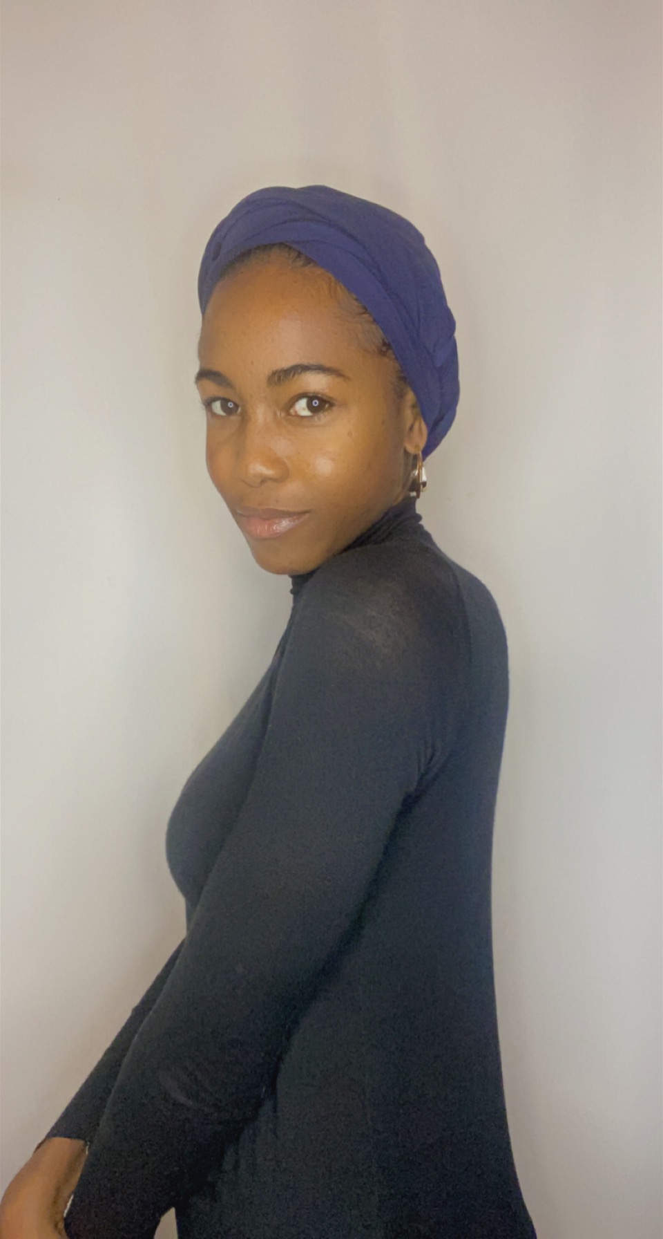 Side profile of a woman wearing a deep iris Krown styled as a smooth turban