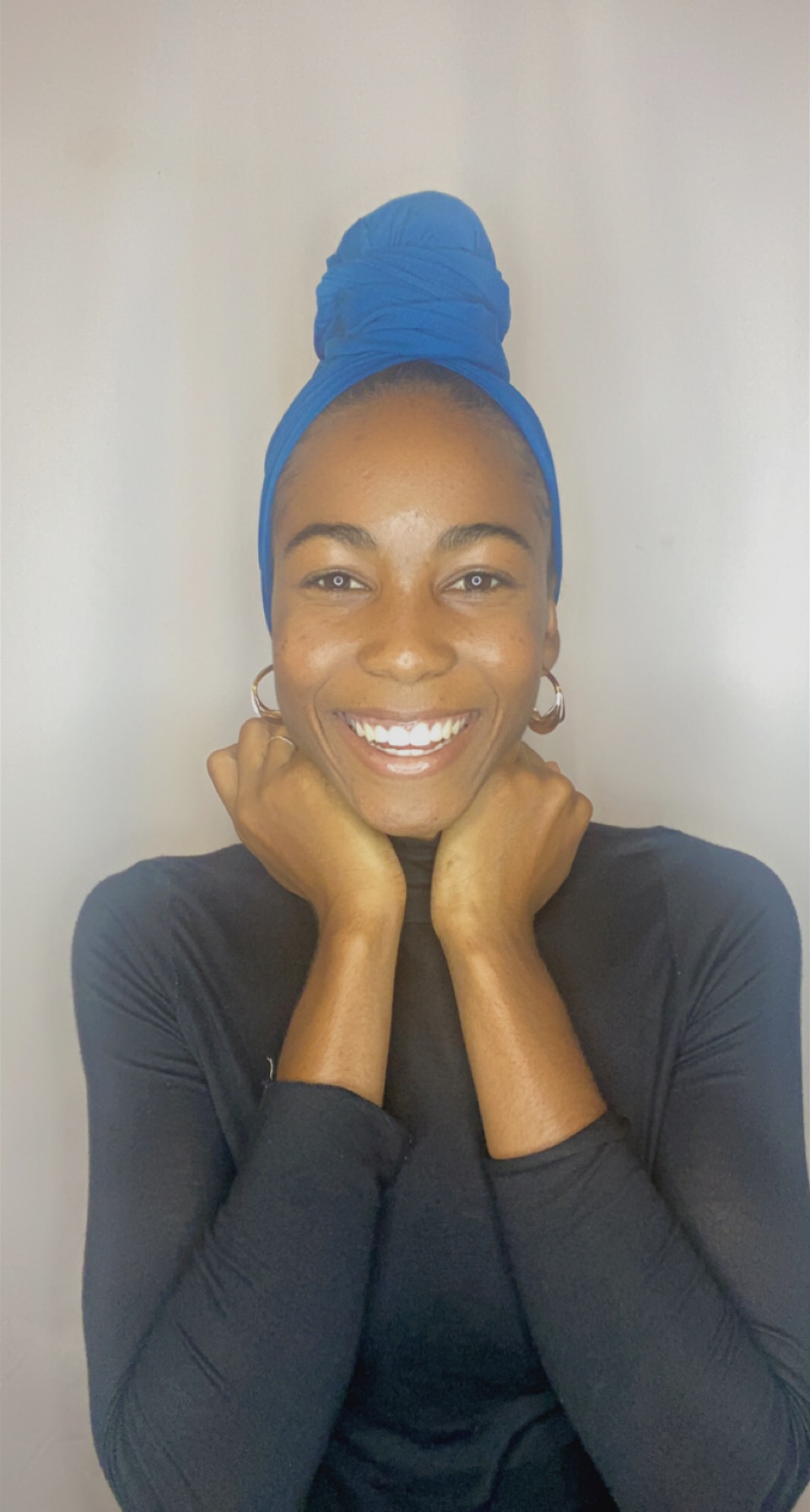 Woman laughing brightly in a royal blue Krown topknot wrap