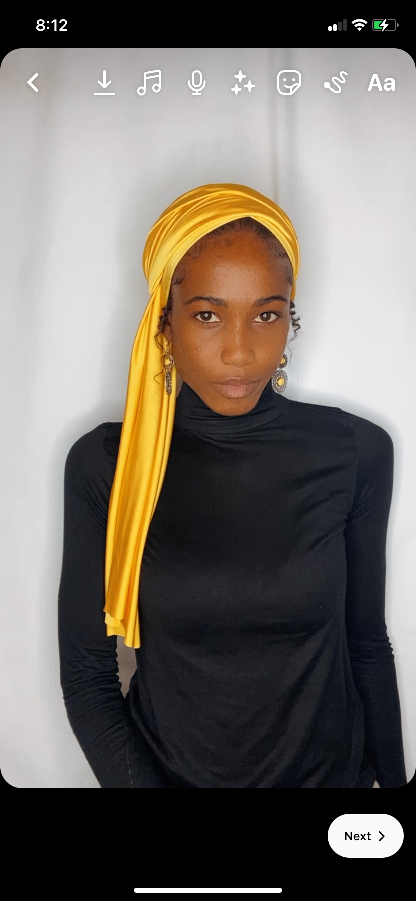 Woman wearing a saffron yellow Krown draped long over her shoulder with a black turtleneck