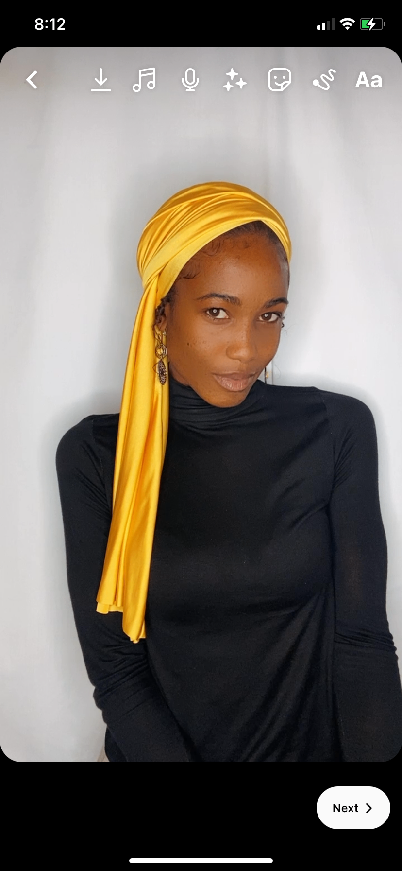 Portrait of a woman wearing a fully wrapped saffron yellow Krown with statement earrings